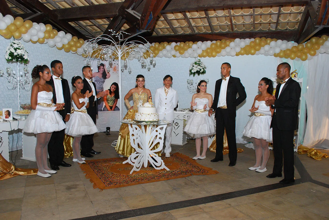 Convidados reunidos junto à mesa durante festa de 15 anos