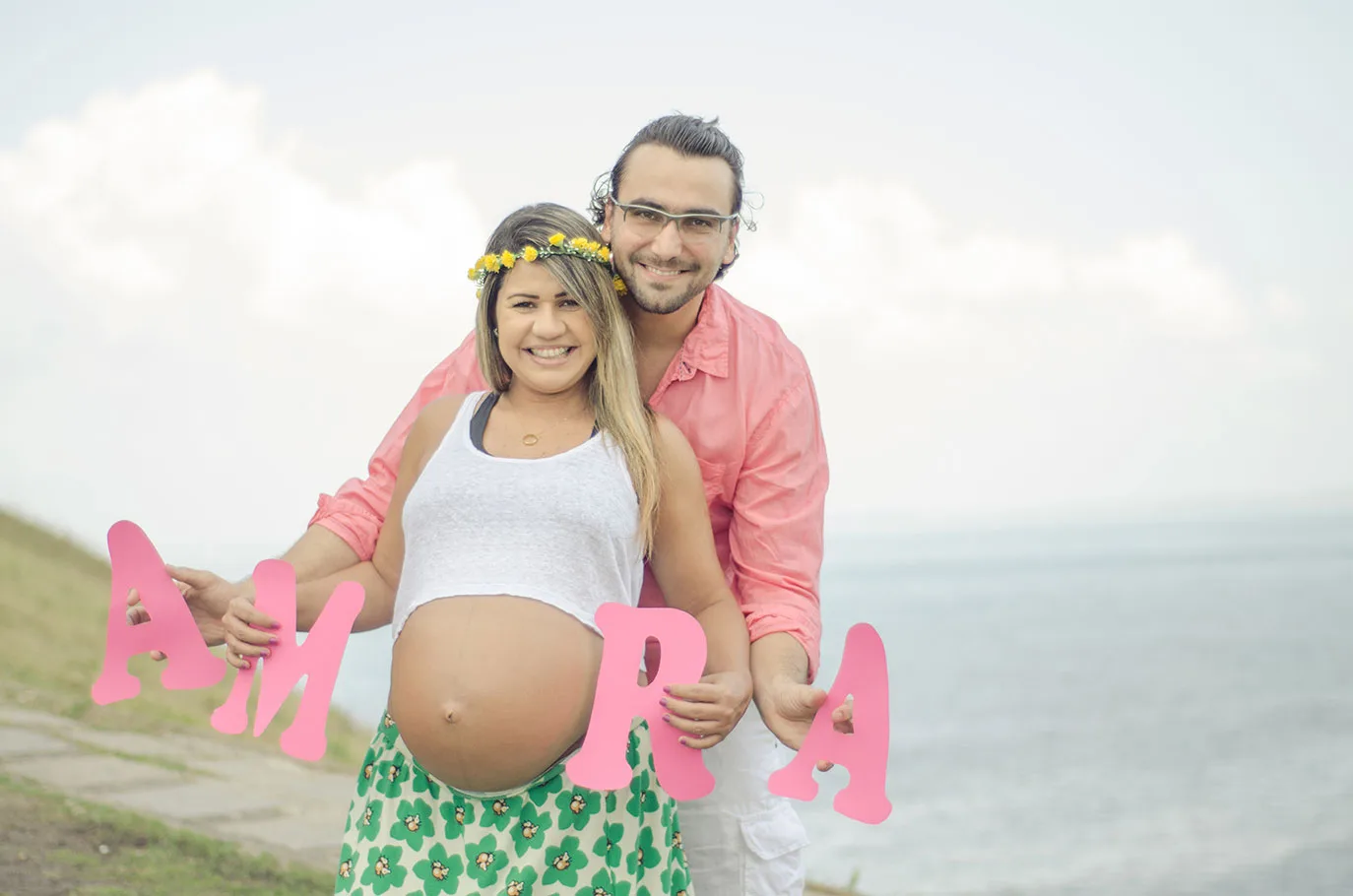 Casal à beira-mar em ensaio de gestante com letras decorativas